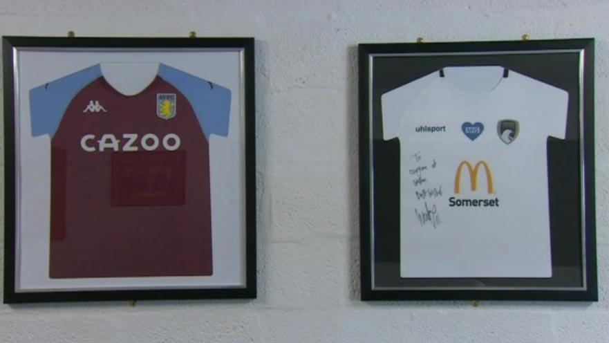 Two framed football shirts beside each other on a white wall