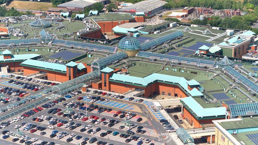 An aerial shot of a large building with a glass dome with a car park surrounding it.