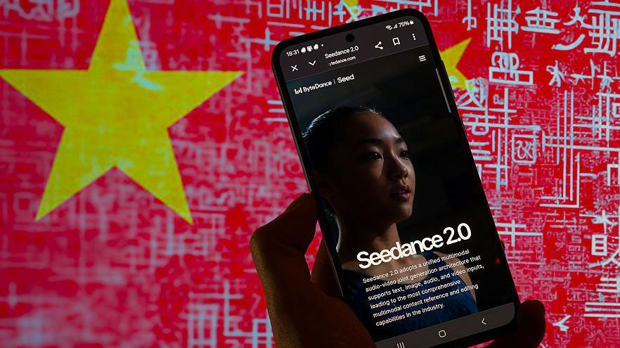 The homepage of the Chinese AI video generation model Seedance 2.0 displayed on a mobile phone, which is held in front of a background with China's flag