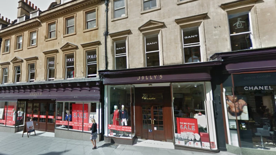 An external view of Jolly's with its well-known purple-painted facade and several red sale signs in the windows.