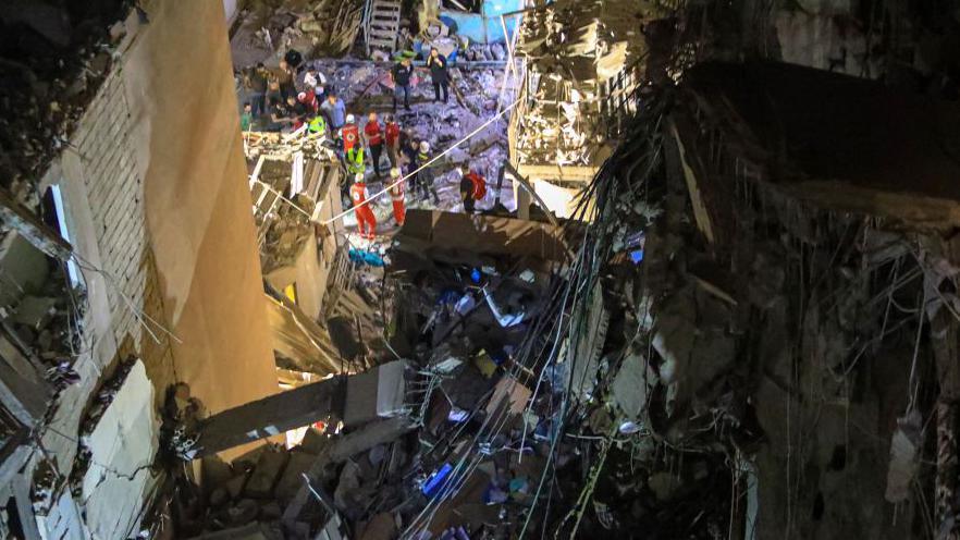 Aerial view showing rescuers working among debris of destroyed building working at night