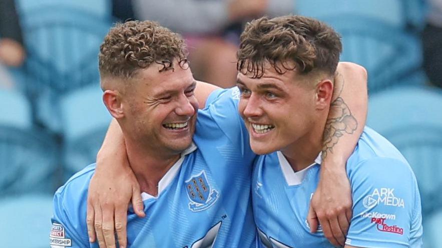 Ben Kennedy celebrates with scorer Ethan Devine after scoring Ballymena's third goal