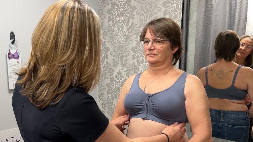 A customer in a shop having a consultation in a changing room with a bra specialist.