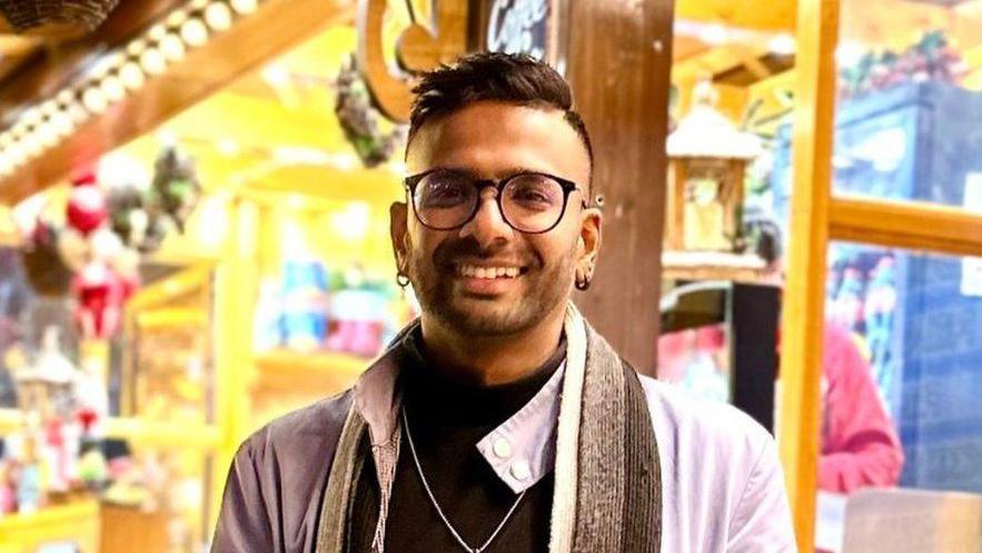 A profile image of Sri Lankan student Oshada Jayasundera standing in front of a market stall