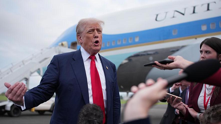 Donald Trump stands speaking to journalists in front of Air Force One