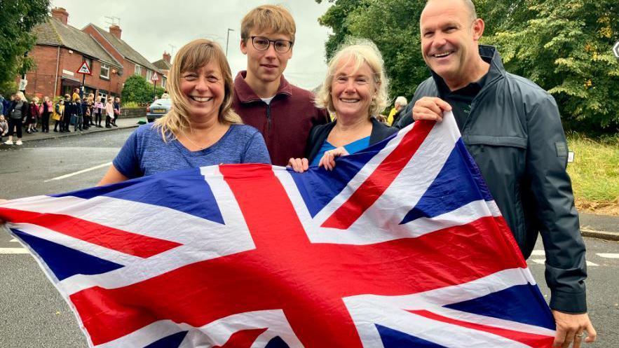 Adelle Fearne, Jaxon Fearne, Carole Miller and Lester Miller watching the race in Outibridge, holding a union flag
 