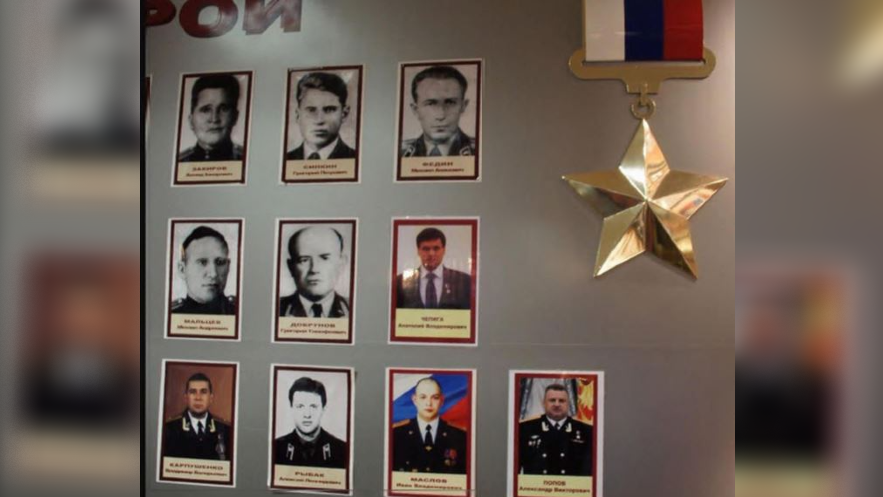 A wall with a large star medal and portrait photos of a number of men.