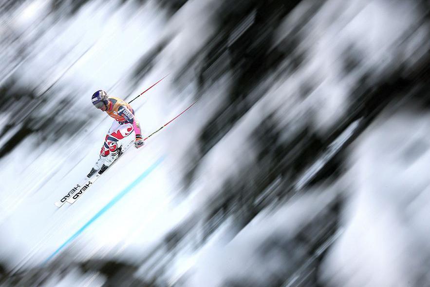 Downhill skier Flavio Vitale races through a snowy course, with the background blurred, emphasising speed and intensity