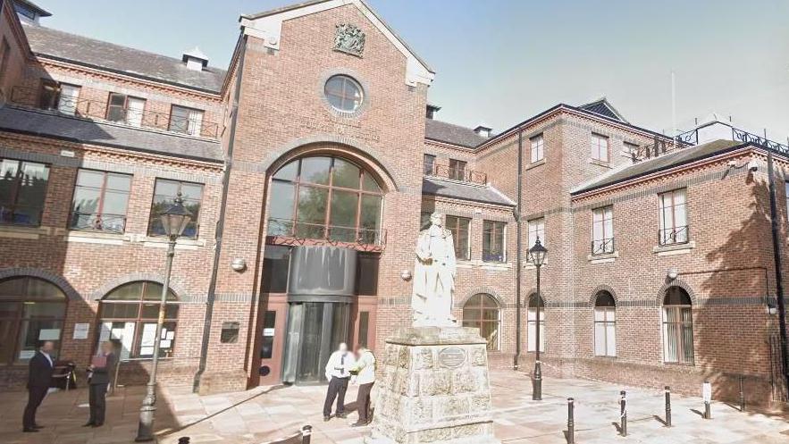 Carlisle Crown Court, a red-brick building with a statue in the middle of the courtyard.