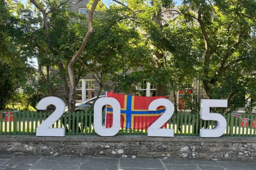 A 2025 handmade sign to show support for the 2025 island games, with orkney flags in the background