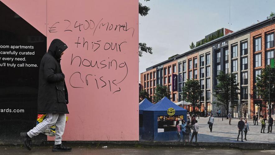 Man passes graffiti relating to rental prices