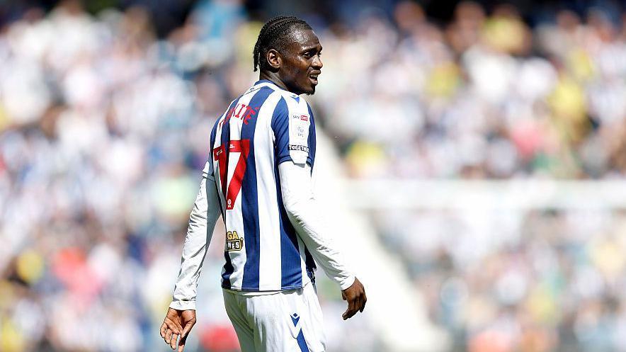 Ousmane Diakite wearing a blue and white striped West Brom playing shirt during a game with a red number 17 on his back