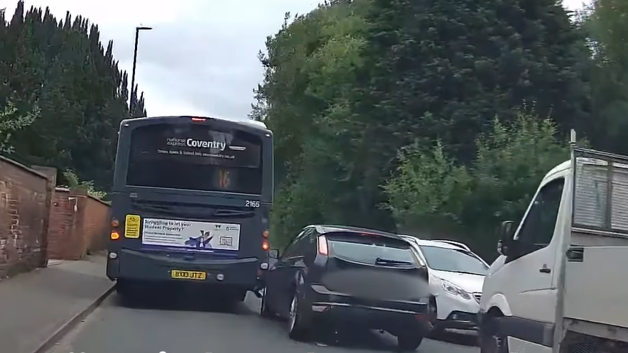 A dark blue ford crashed into the back of a bus and a white car