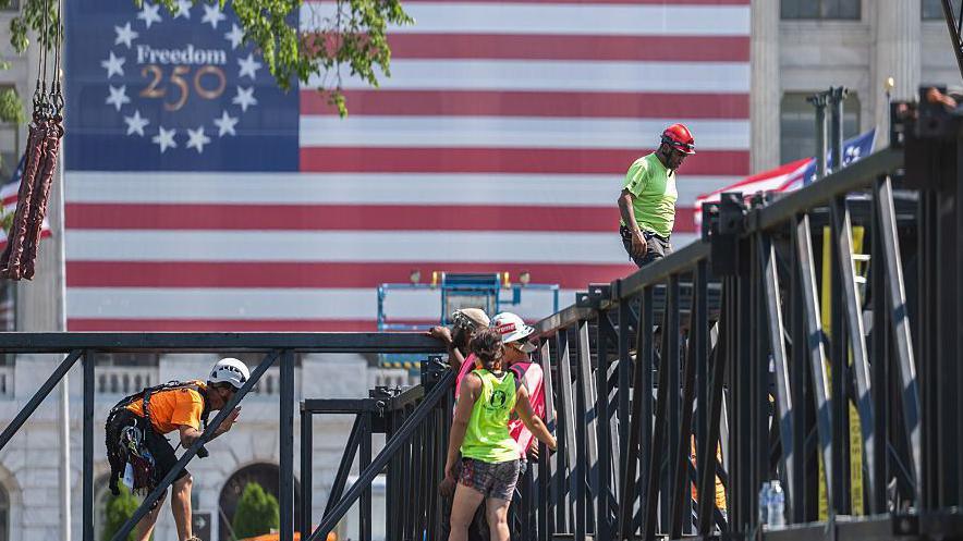 Workers construct structures for the Great American State Fair on the National Mall with the US flag in the backdrop