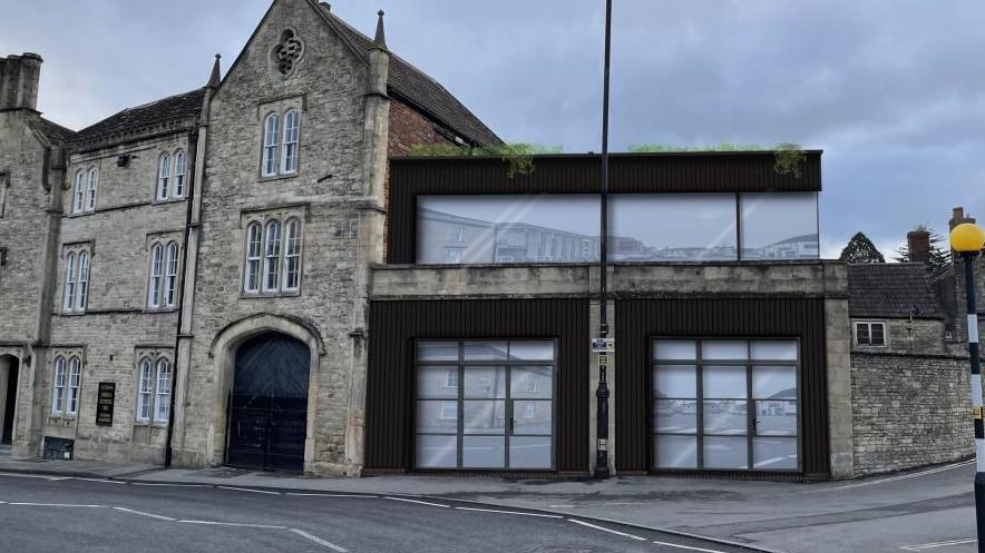 A CGI of glass panels on a black building front, next to a stone building