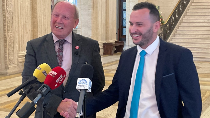 Jim Allister and Timothy Gaston smile and shake hands in the great Hall of Stormont