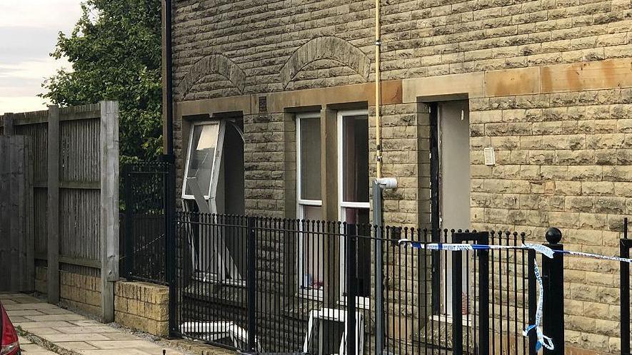 Police tape around a property which has its windows blown out after a blast