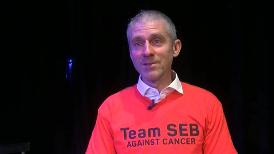 Teacher Chris Johnson with his head shaved and wearing an orange T-shirt that says: 'Team Seb against cancer'