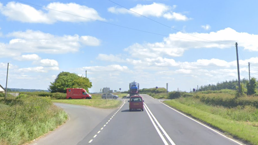 A google image of vehicles on the road near Stopgate Cross on the A303. There is greenery to the edges of the road, and blue skies.