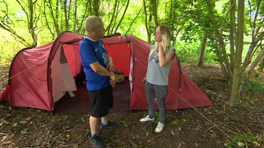 Couple talking to each other outside of their tent