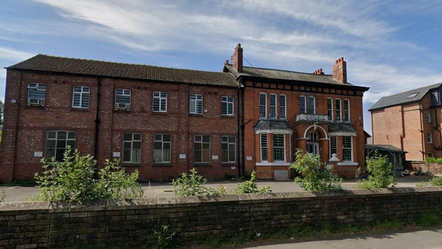 A street view of the former school before it was partially demolished: a two-storey red-brick building, with original Victorian architecture on the right.