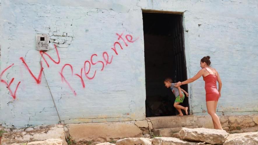 A wall of a house is marked with graffiti reading "ELN present" as a woman and a small boy enter a doorway to the right, in the Seis de Enero neighborhood in the city of Cucuta, Colombia, 04 July 2023, 