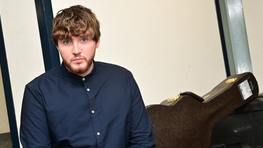 James Arthur seated next to a guitar case