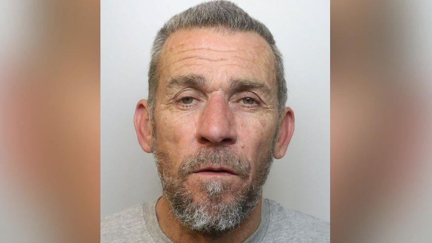 Mugshot of Gary Selwood. He has grey hair and a beard and is wearing a grey shirt.