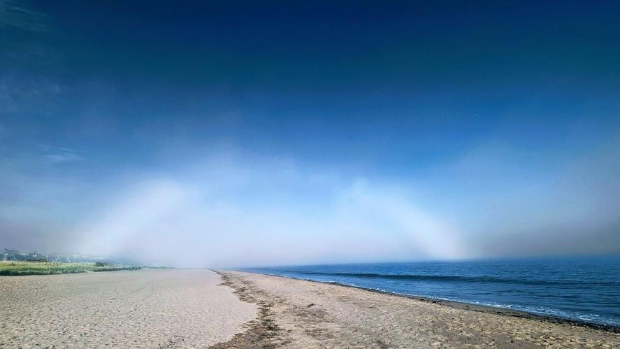 A fogbow forms above a beach and the sea at Broughty Ferry