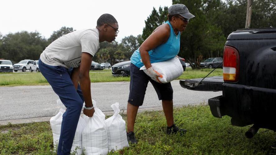 Shon Rodriguez and his mother Millie load their car with sandbags