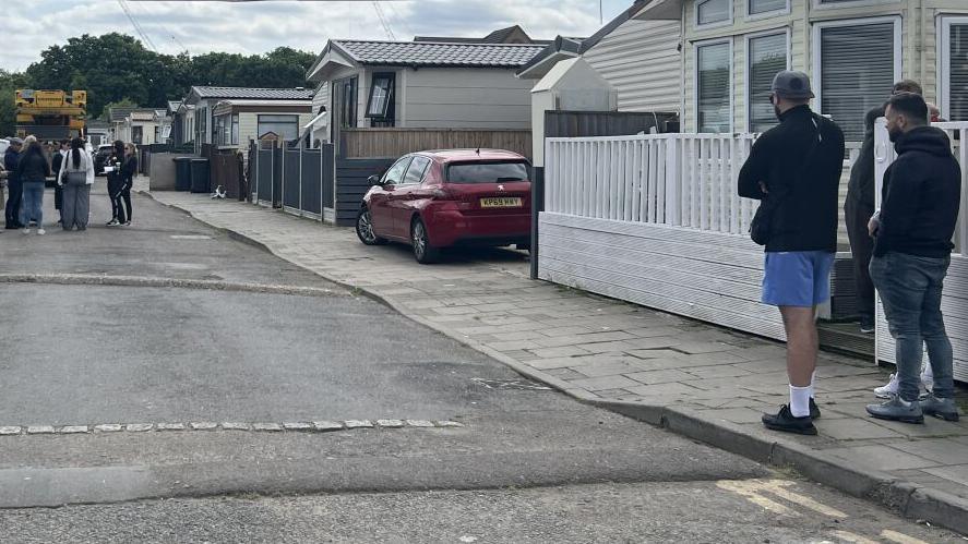 A general view of the Traveller site, where people are seen people are walking around in front of mobile homes.