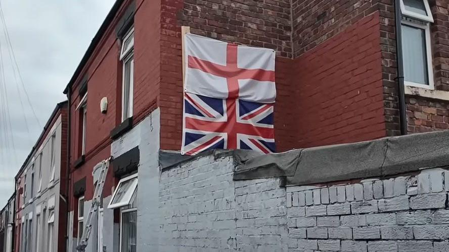 Union flag and St George's flag on the side of a terraced house