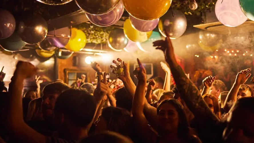 Clubbers hold their hands in the air on a packed dancefloor. 