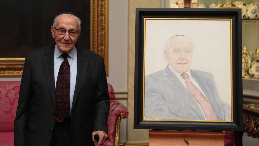 Holocaust survivor Manfred Goldberg poses beside a portrait of himself during a reception marking Holocaust Memorial Day at Buckingham Palace on January 13, 2025 in London, England
