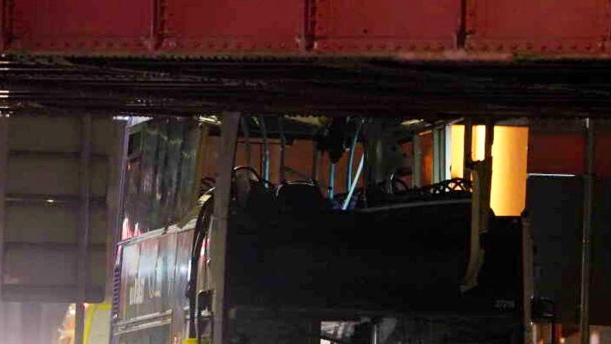 Front view close up of a bus wedged under a railway bridge