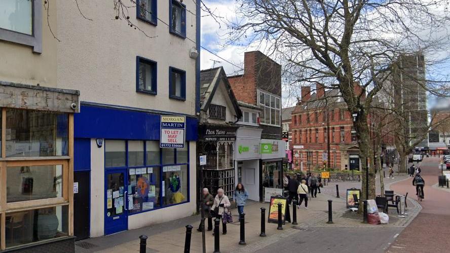 Shoppers walk past the empty blue betting shop that will soon be turned into a homeless centre