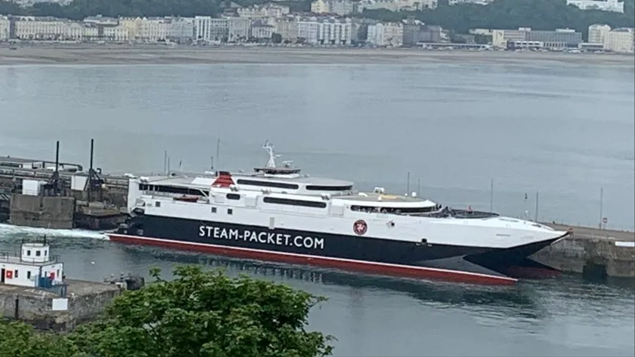 The Manannan moored in Douglas Harbour. It is painted in the Isle of Man Steam Packet Company's colours of red, black and white. It has Steam-Packet.com on the side of the hull in white lettering.