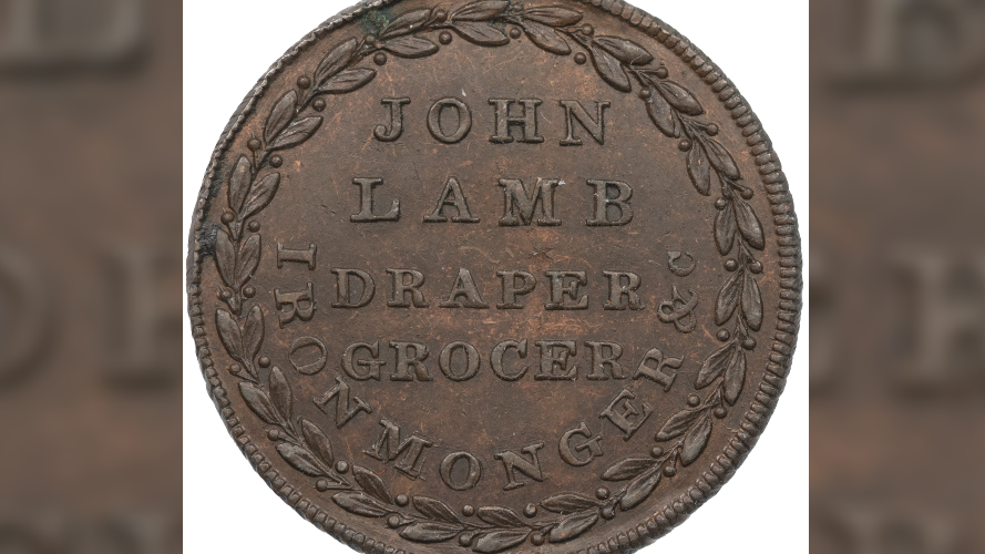 An old copper coin well-preserved with leaves round the edge and in the middle declaring it is from 'John Lamb: draper, grocer, ironmonger'