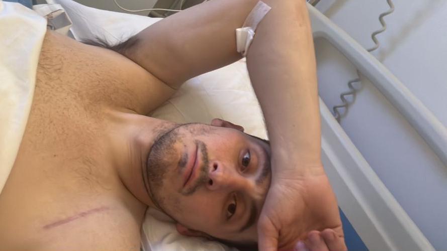 Sam Davies yn gorwedd ar wely ysbyty