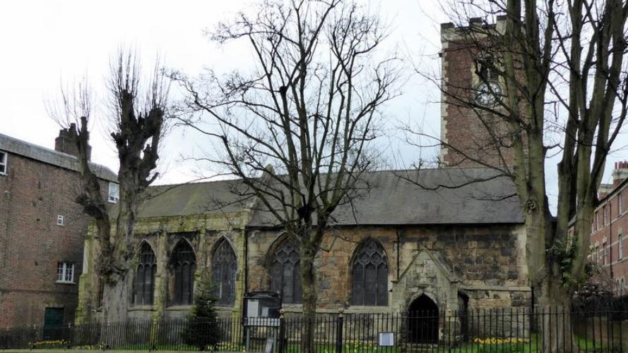 The Grade I listed St Martin-cum-Gregory Church on Micklegate in York, a traditional stone church with a clock tower and trees in the foreground.