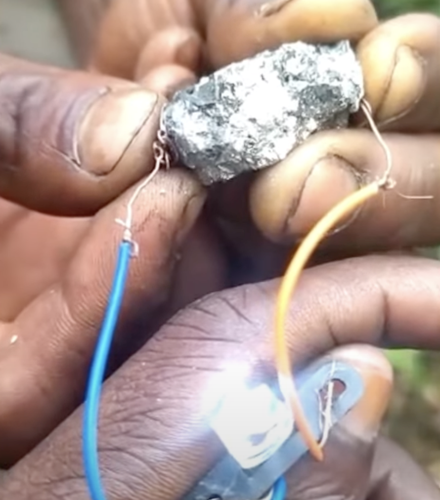 A man's hands holding a rock and a lit bulb