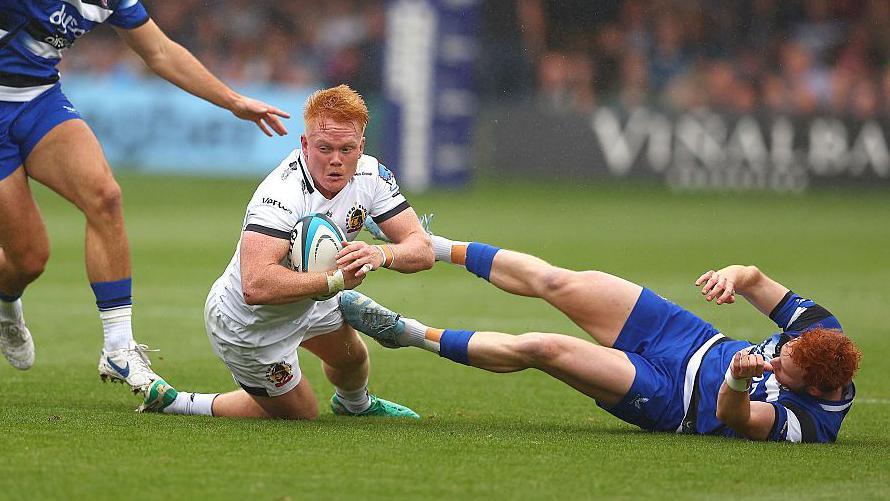 Exeter's Ben Hammersley, in white, goes to ground with two Bath defenders trying to tackle him.