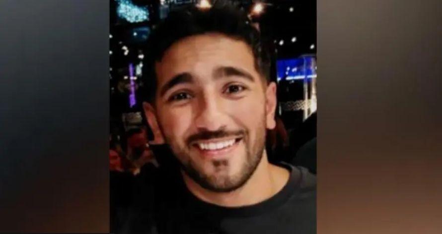 Image of Rehaan smiling at the camera. He is wearing a black t-shirt. Behind him a nightclub can be seen.