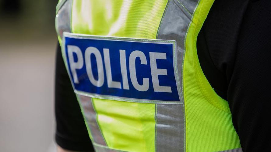 A stock image of a police officer wearing a hi-vis jacket with the word "Police" on the back.