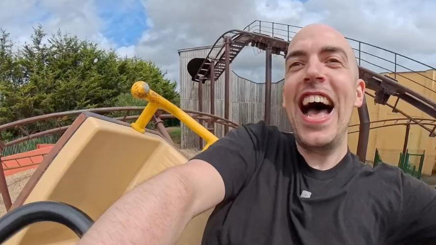 A selfie of Dean Stokes on top of a rollercoaster laughing
