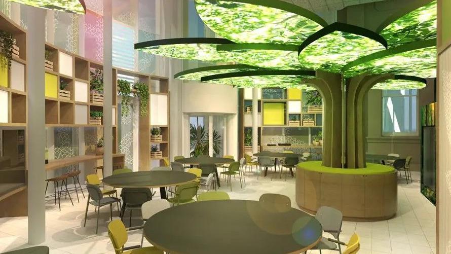 An artist's impression of the growing space which is green and a light display shaped like a tree. There are rows of bookcases and round tables. 