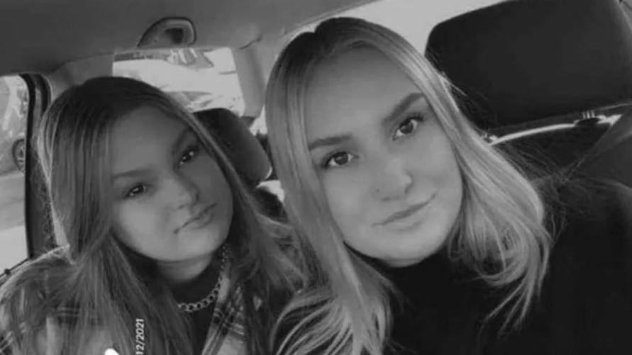 Two sisters sitting in car wearing black and checked top. 