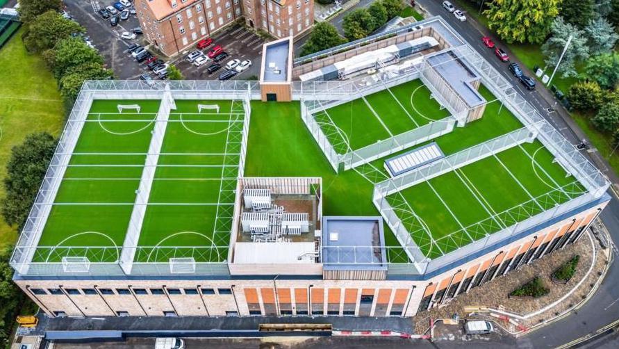 An aerial view of the rooftop football pitches at Eclipse Leisure Centre. A number of green football pitches can be seen on top of a building.