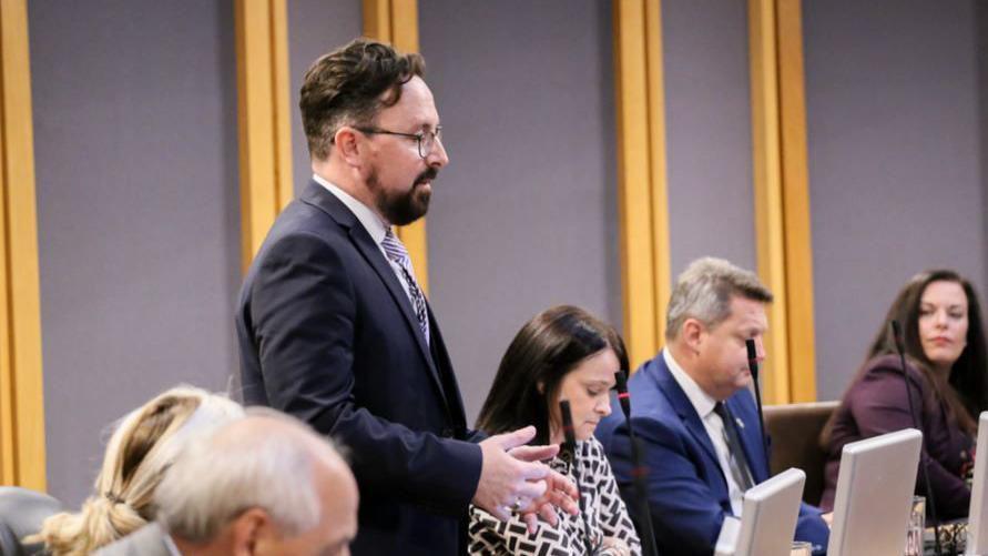 Hefin David in the Senedd. He has a brown beard and brown short hair. He wears black square glasses.