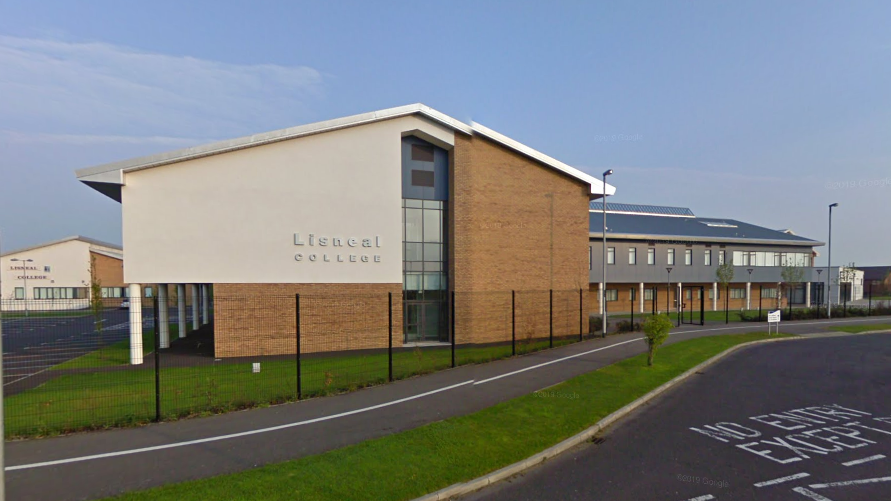 A screengrab of Lisneal College from Google Maps.  The large brown brick and grey render building has a slanted roof. It is surrounded by grass and a black security fence.